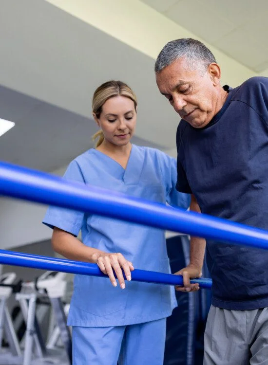 senior man practices physical therapy exercise with the help of his caregiver