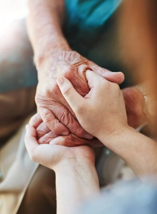 close-up of senior man clasping hands with his caregiver
