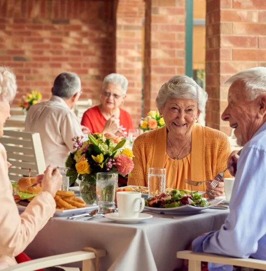 group of well-dressed seniors smile while dining outdoors together and conversing