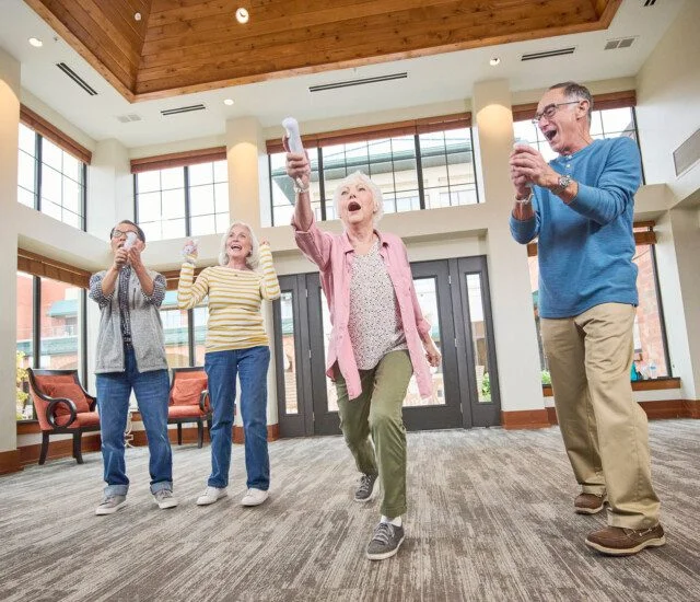group of senior friends playing Wii games together in the lounge at their senior living community