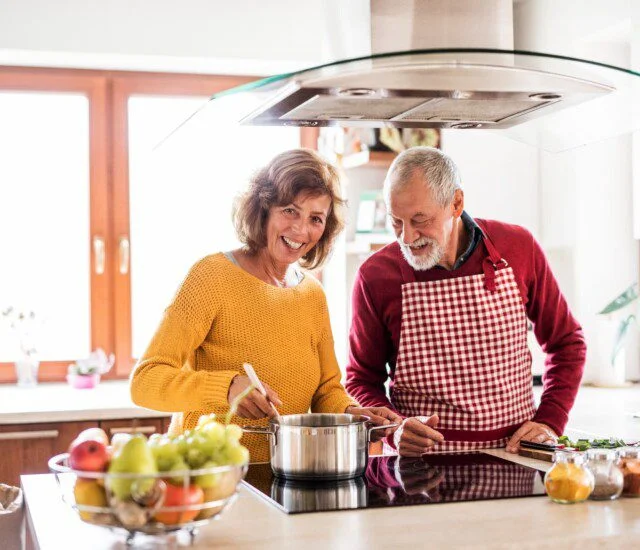 A senior man and senior woman cooking together nutritious recipes