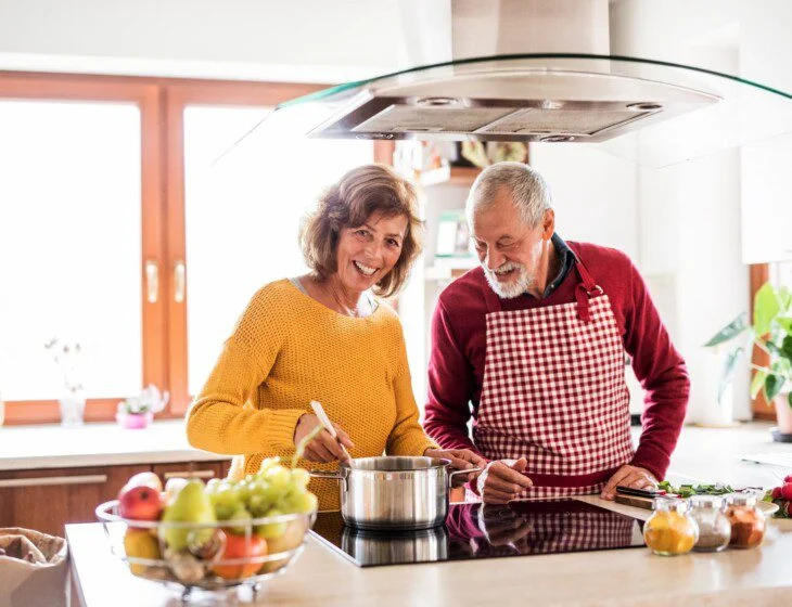 A senior man and senior woman cooking together nutritious recipes