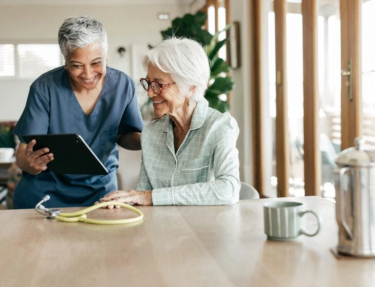 A compassionate nurse helping an elderly woman understand her healthcare options at home.