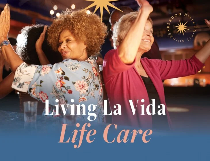 Two senior women dancing back to back with their hands in the air with text: Living La Vida Life Care.