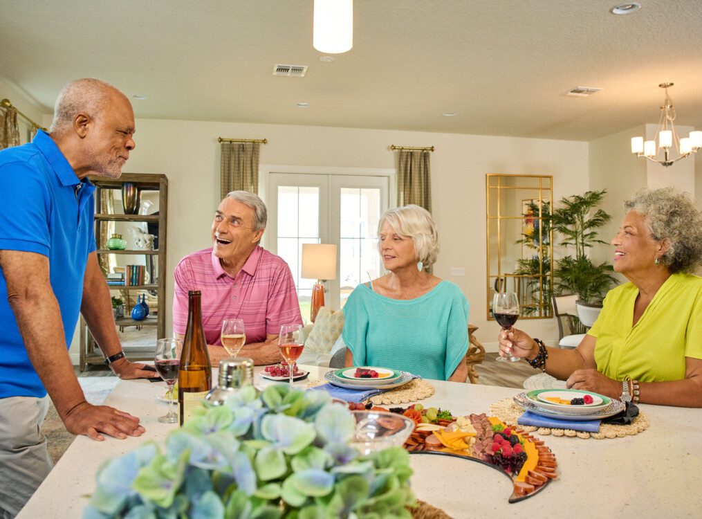 group of seniors gather in a villa home for snacks, drinks, and games