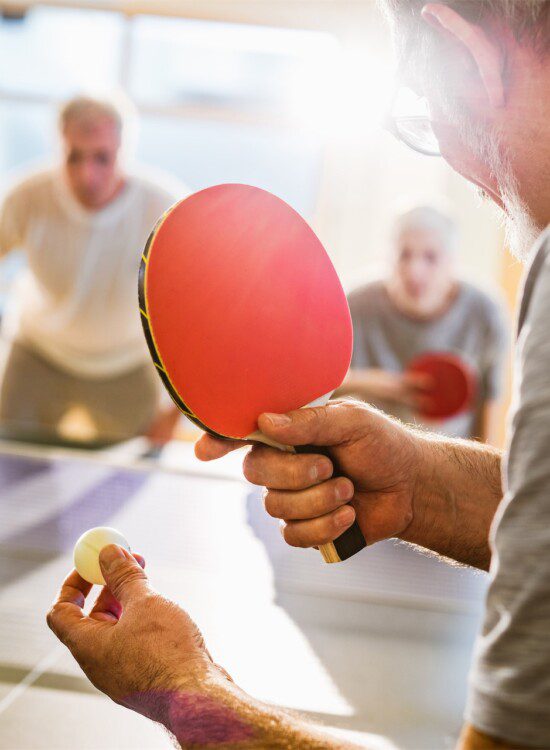 group of senior friends play ping-pong together