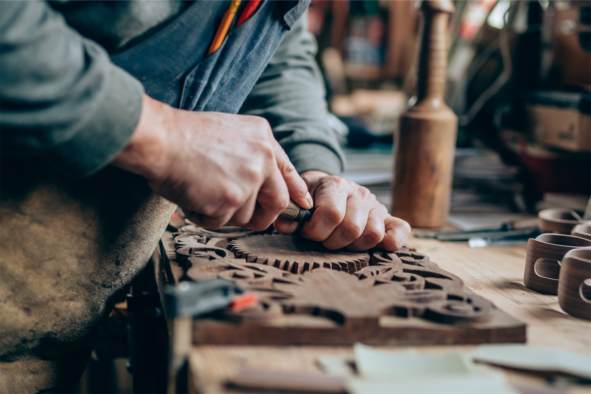 close-up of senior man using carving tools to create intricate wood pattern