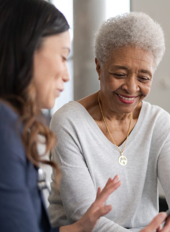 senior woman is shown information by her caretaker while seated