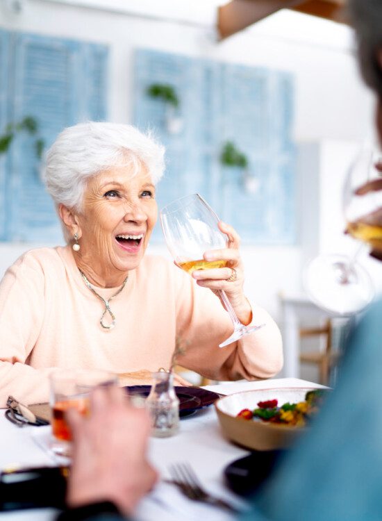 senior couple smiles and drinks wine together in a formal dining venue