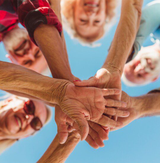 group of seniors put their hands together in a circle, a team cheer