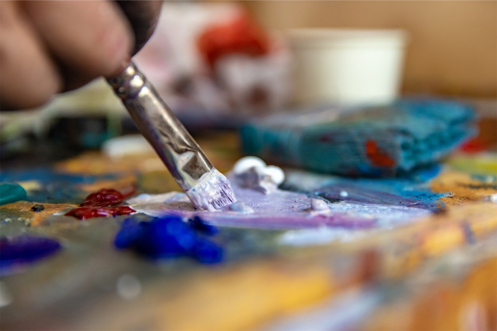 close-up image of paint brush dipping into paint on palette