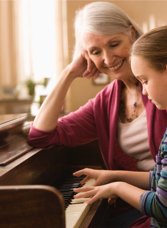 grandmother teaches granddaughter how to play the piano
