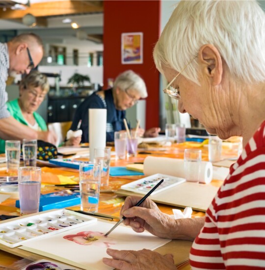 Group of seniors take painting class at their senior living community