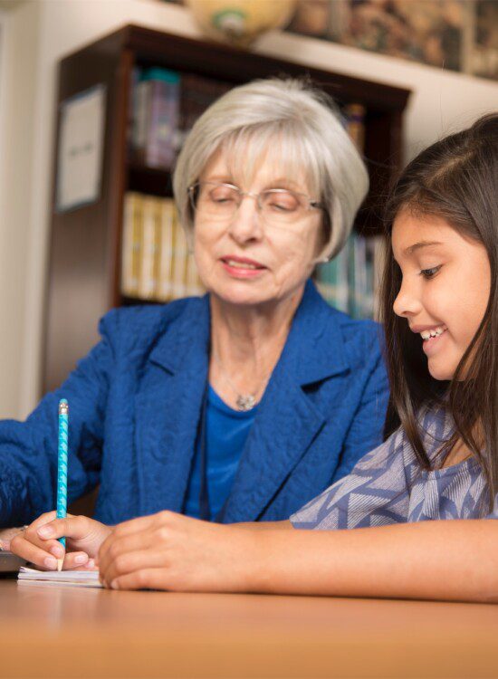 grandmother and granddaughter writing in library