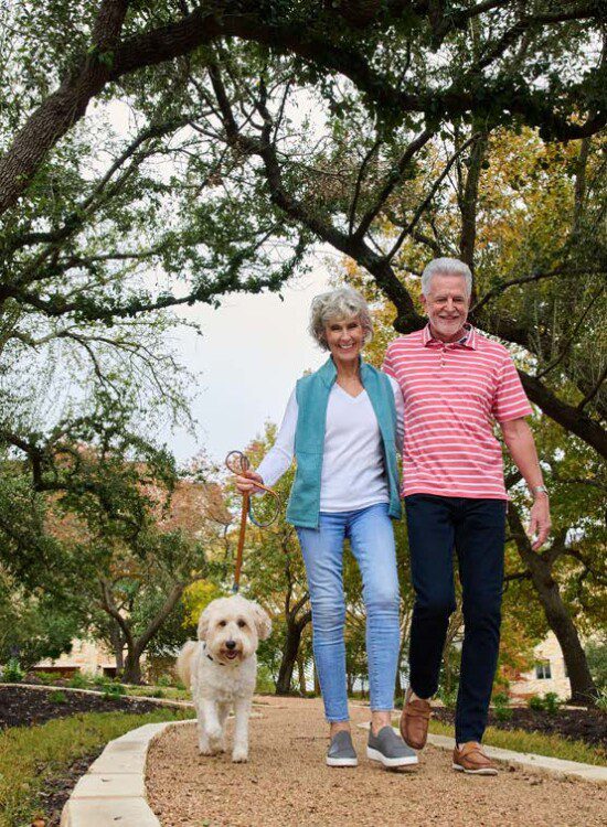 senior couple walks their small dog on a scenic path outdoors
