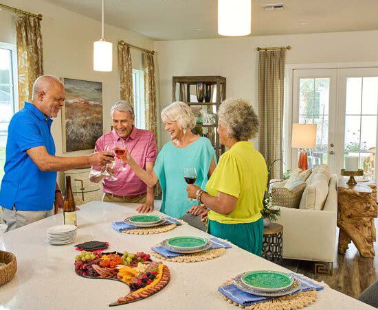 group of seniors smile and toast wine glasses in a villa at their Senior Living Community