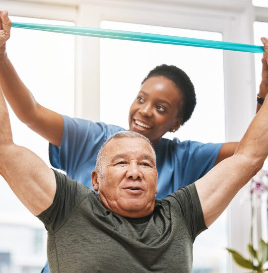 senior man practices physical therapy exercise with the help of his caregiver