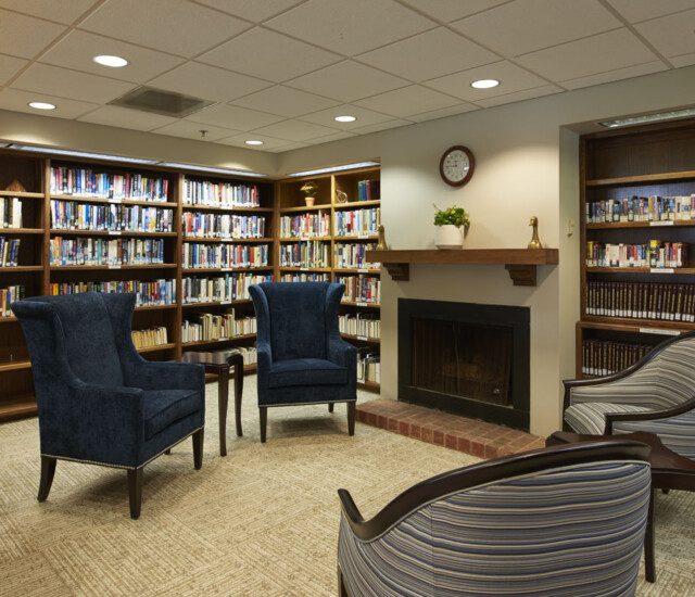 cozy library with chairs and fireplace at Beacon Hill Senior Living Community