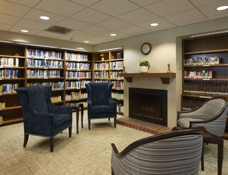 cozy library with chairs and fireplace at Beacon Hill Senior Living Community