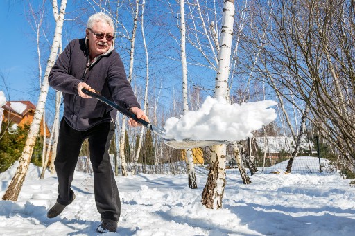 senior man shoveling snow on a sunny day