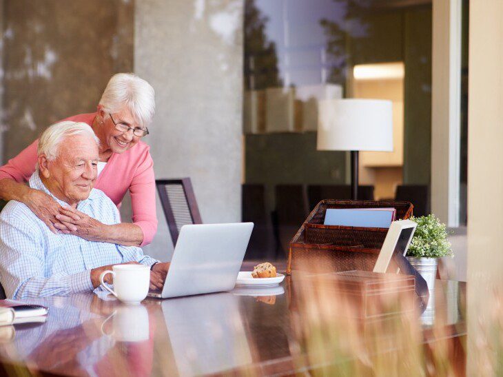 senior couple smiles while video calling loved ones on their laptop