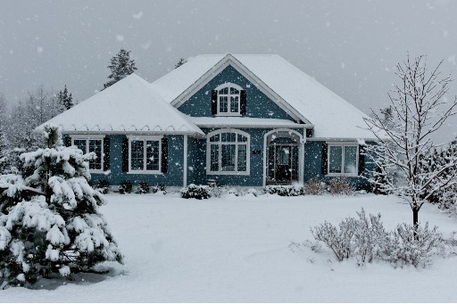 dark blue house covered in lots of snow as the snow continues to fall