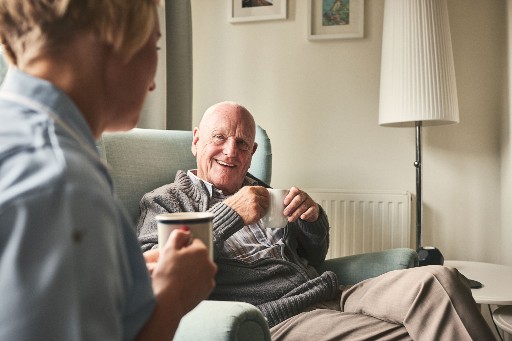 elderly man having a cup of coffee with a nurse in a retirement home