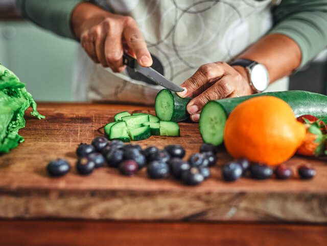 close-up of older woman chopping vegetables for a meal