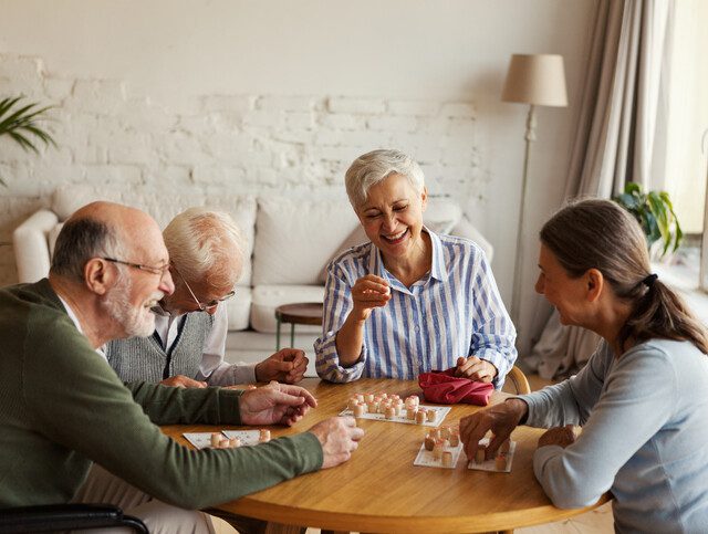 group of senior friends smile and play table games in one of their homes