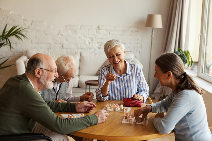 group of senior friends smile and play table games in one of their homes