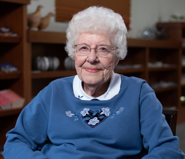 Senior woman (Joan Vogel) sits in a chair and smiles for an interview