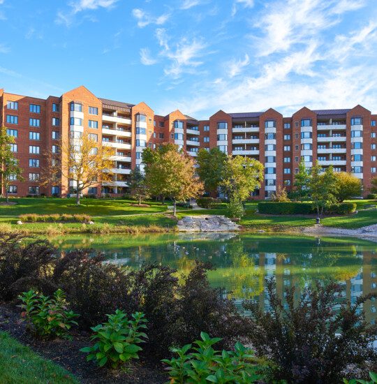 scenic walking path adjacent the pond and a residential building at Beacon Hill Senior Living Community