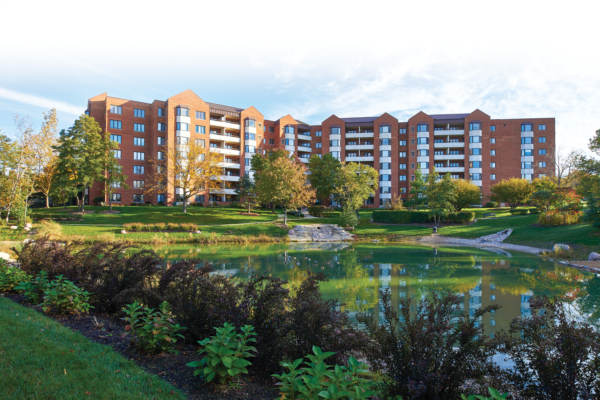 view of pond and green landscaping outside of a residential building at Beacon Hill Senior Living Community