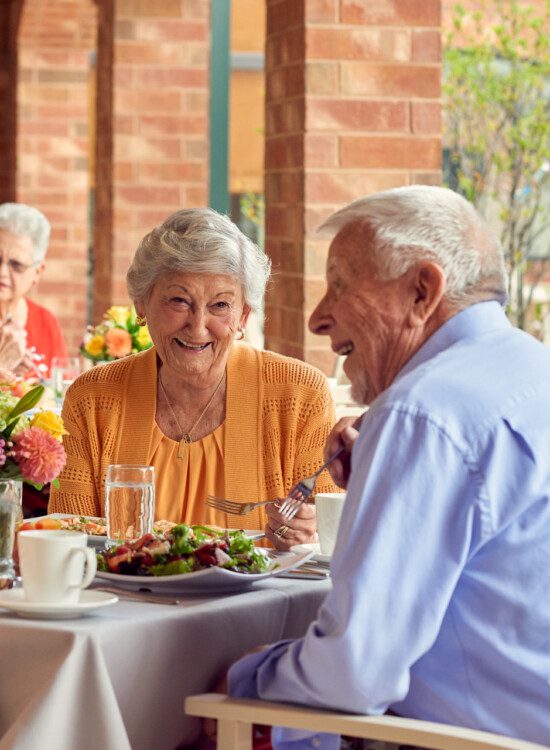 well dressed senior couple smiles and enjoys an outdoor dinner at Beacon Hill Senior Living Community