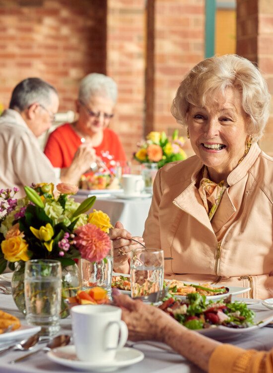 group of well-dressed seniors smile while dining outdoors together and conversing