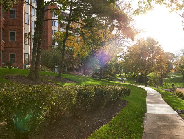 scenic walking path adjacent the pond and a residential building at Beacon Hill Senior Living Community