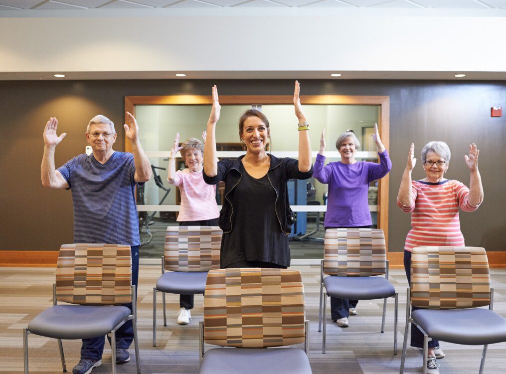 group of seniors practice chair exercises in their senior fitness room