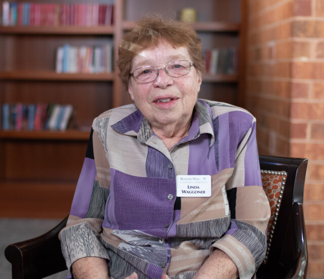 Senior woman (Linda Wagooner) sits in a chair and smiles at the camera for an interview