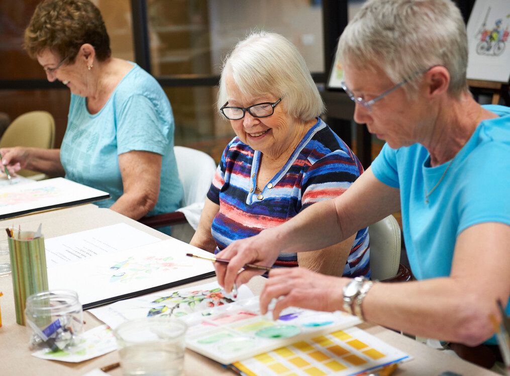 senior woman and friends work on watercolor paintings during class at Beacon Hill Senior Living Community