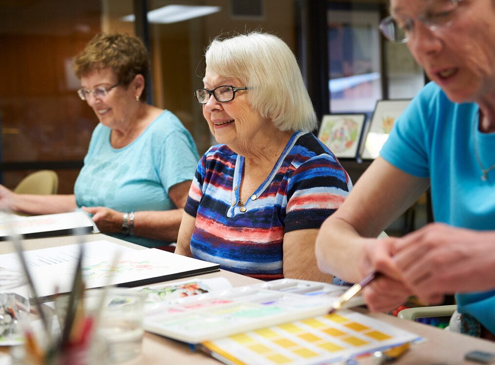 senior woman pays close attention during a watercolor painting class with friends at Beacon Hill Senior Living Community