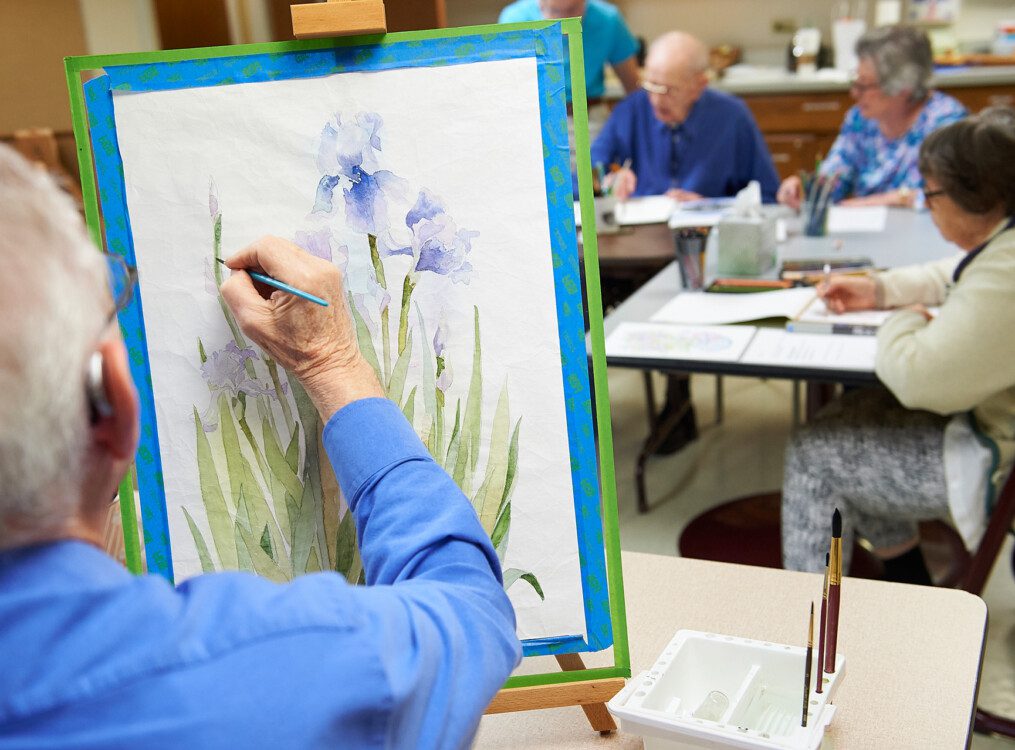 close-up of senior main painting watercolor flowers during a class at Beacon Hill Senior Living Community