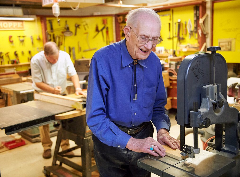 senior man uses saw while completing woodworking project at Beacon Hill Senior Living Community