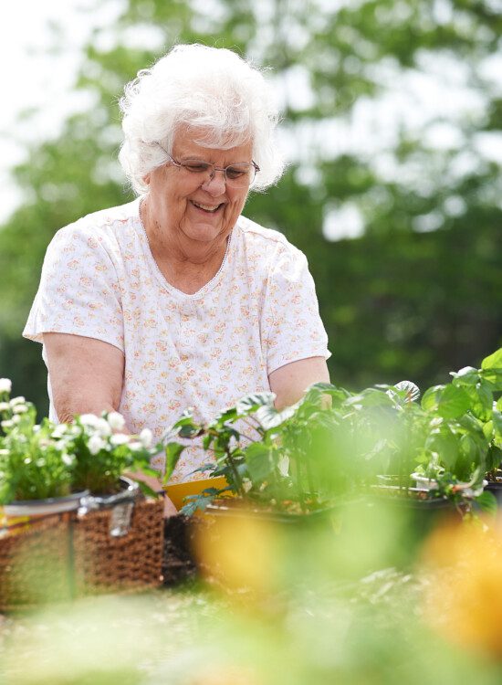 smiling senior woman works in outdoor community garden at Beacon Hill