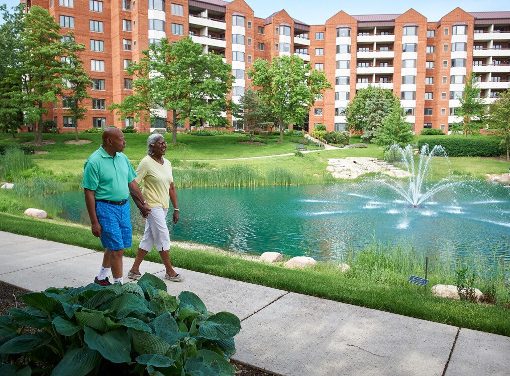 smiling senior couple works cheerfully in the outdoor community garden at Beacon Hill Senior Living Community