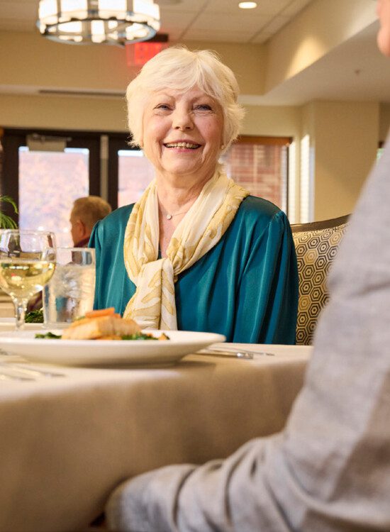 group of well-dressed senior friends enjoying a meal together in an elegant setting by a glass fireplace