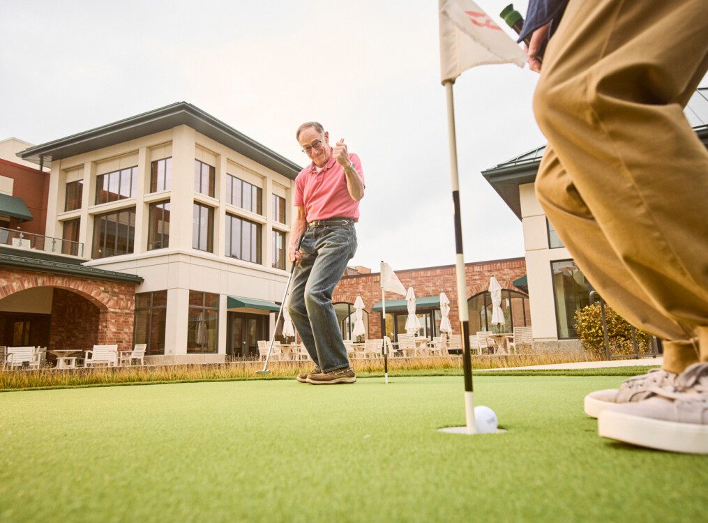 senior man celebrates while playing a round of golf outside at Beacon Hill Senior Living Community