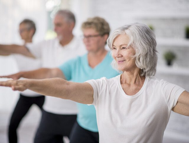 group of seniors practice yoga and smile