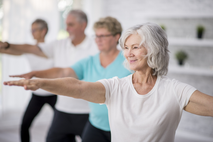 group of seniors practice yoga and smile