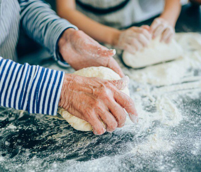 senior woman and her grandson knead dough to make bread