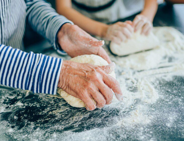 senior woman and her grandson knead dough to make bread